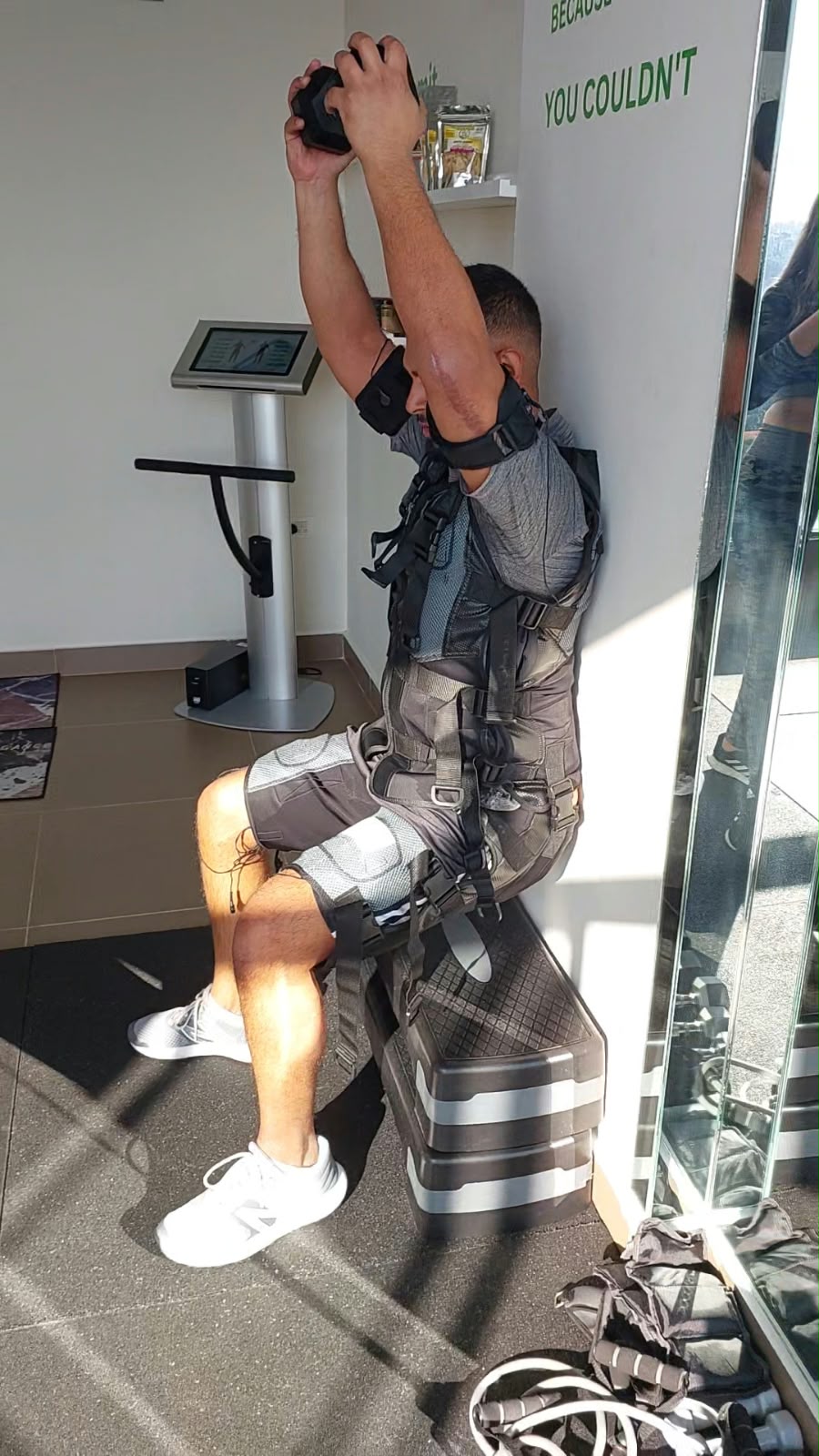 A seated client performing an overhead dumbbell exercise